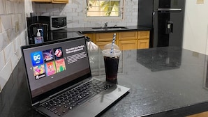 Una cocina con una computadora portátil, un refrigerador, un microondas y un ventanal.