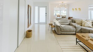 A modern living room with a sectional sofa, a wooden coffee table, and a glass dining table. - Encanto Family, cozy patio & pool, near to everything (Miami)