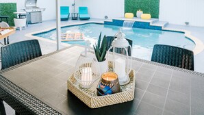 A poolside area with a table set with candles, a lantern, and a tray. - Encanto Family, cozy patio & pool, near to everything (Miami)