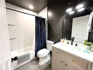 A bathroom with a bathtub, toilet, and vanity with a mirror. - New Modern Ranch Home in Quiet Neighborhood of ATL (Atlanta)