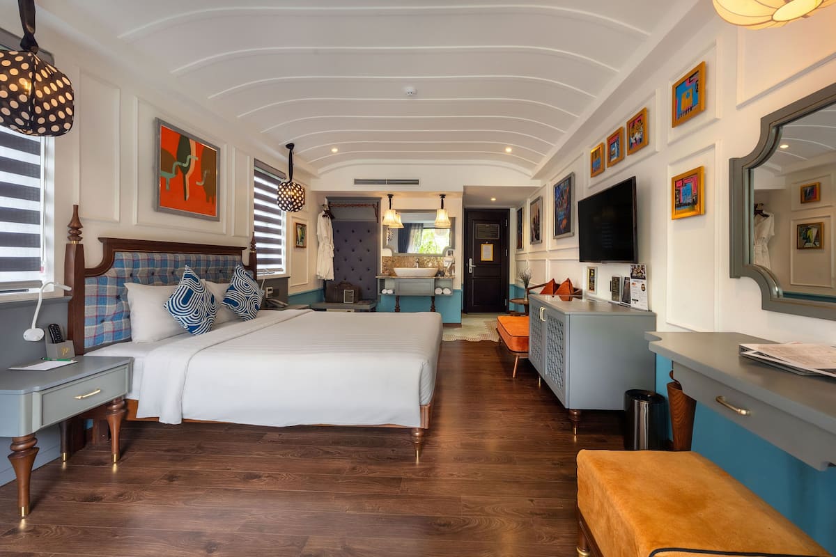 Un dormitorio amplio con una cama grande, un tocador, televisión y un baño a la vista.