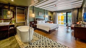 Une chambre d’hôtel avec un grand lit, une baignoire, une coiffeuse avec un miroir et une vue sur l’extérieur.