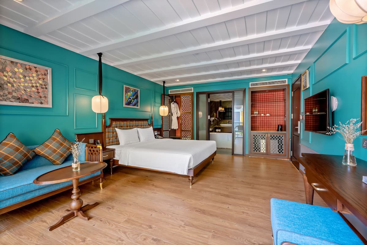 Una habitación de hotel moderna con cama, sofá, una mesita y televisor.