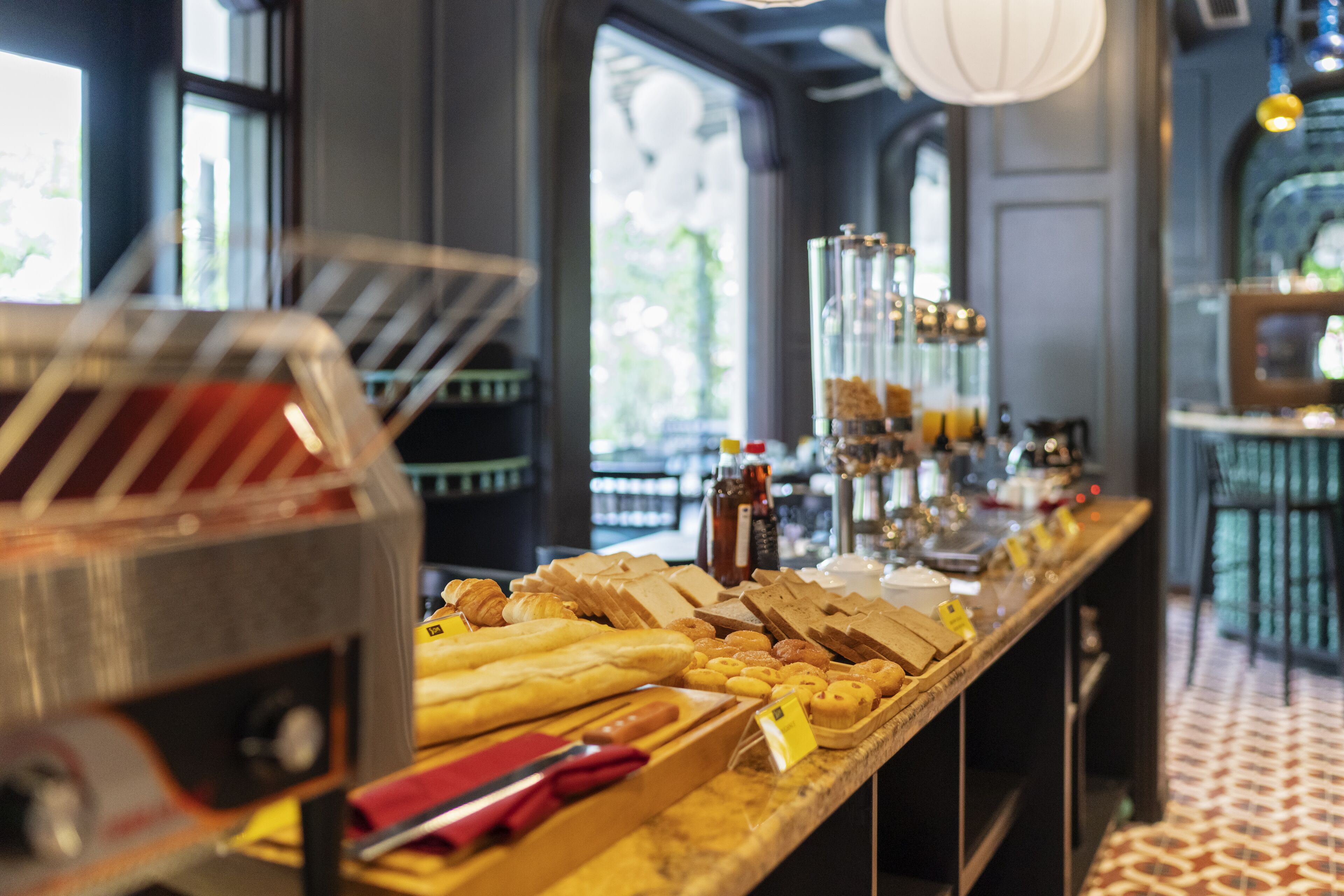 A bakery counter with various pastries and bread, a coffee machine, and a selection of condiments.