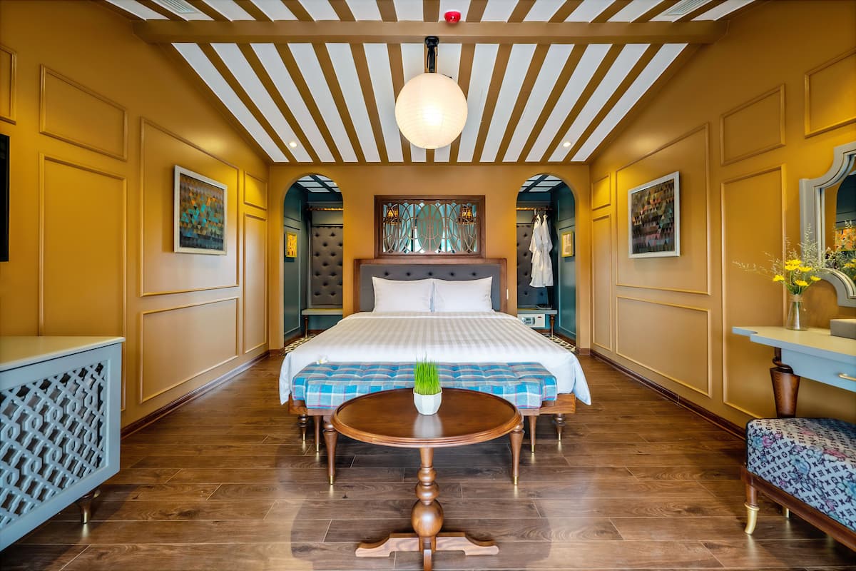 Habitación de hotel con una cama grande, una mesa redonda de madera y un techo con vigas de madera.
