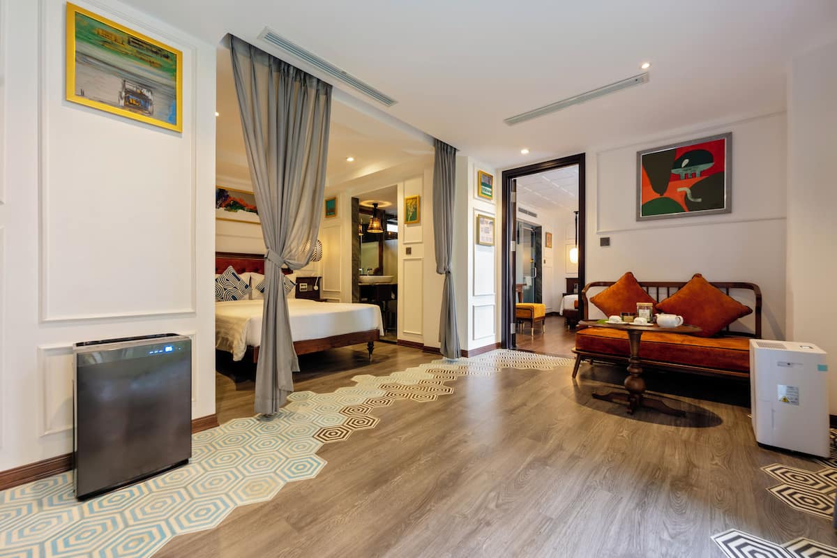 Habitación de hotel con cama, sofá, escritorio, refrigerador y ventana.