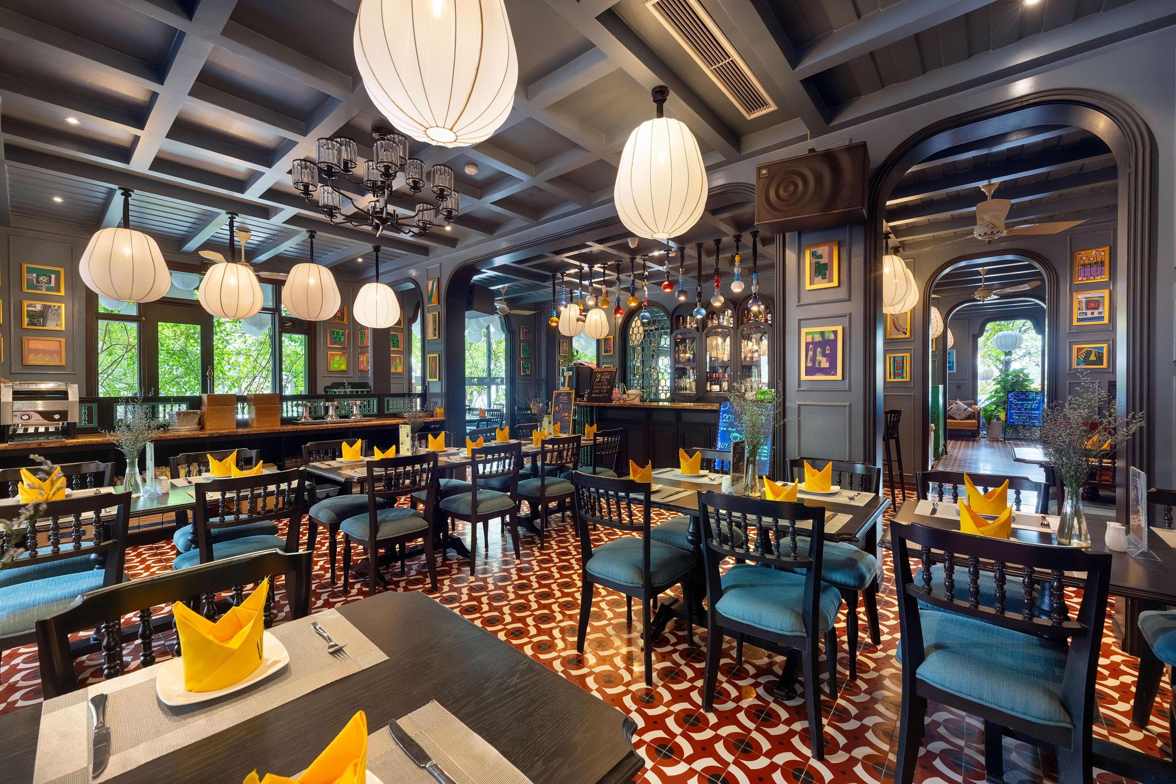 Een restaurant met meerdere eettafels en stoelen, een patroon vloer en hangende吊り下げ型ライト.