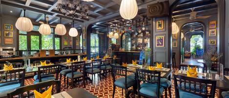 Een restaurant met meerdere eettafels en stoelen, een patroon vloer en hangende吊り下げ型ライト.