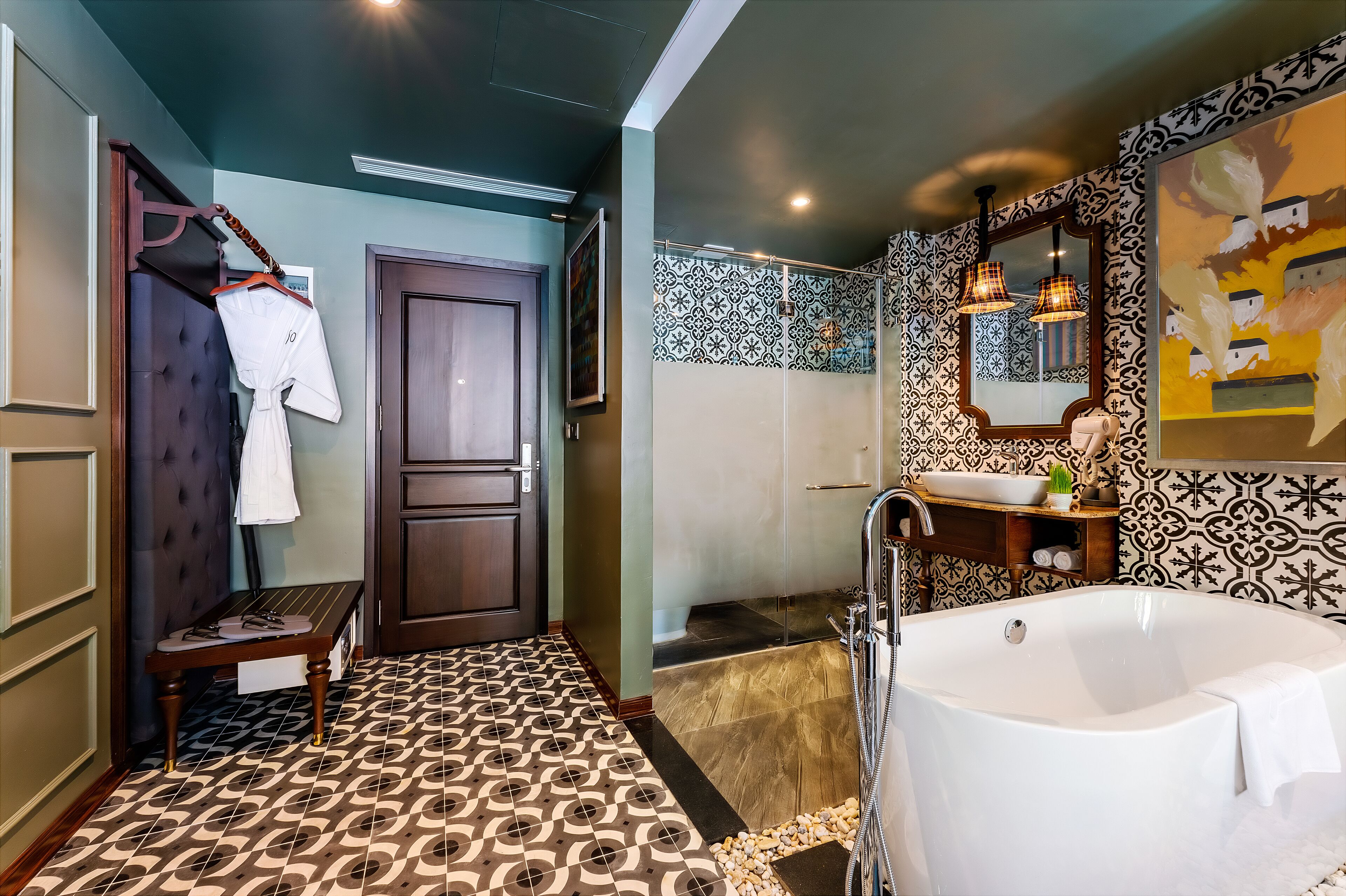 A bathroom with a large bathtub, a sink, and a mirror. There is a bench and a door in the room.