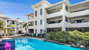 Un hôtel moderne doté de nombreux balcons, d’une piscine et d’un aménagement paysager luxuriant.