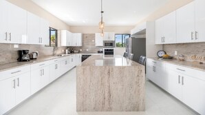 Una cucina moderna con mobili bianchi, un'isola centrale e una lampada a sospensione.