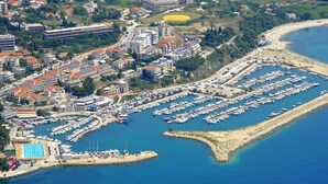 An aerial view of a coastal town with a marina, residential buildings, and a beach.
