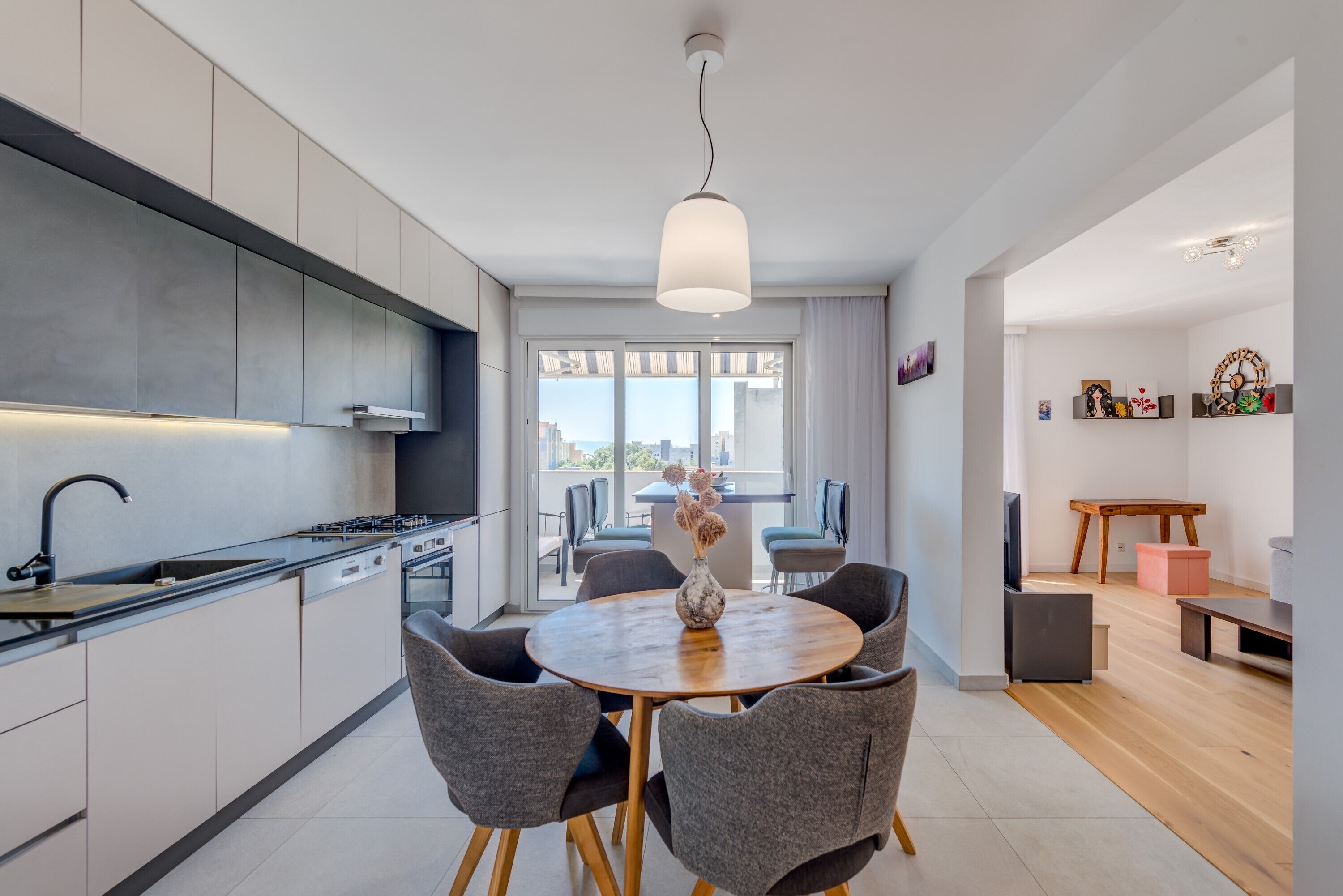 A modern kitchen with a dining area, large windows, and a view of the city.