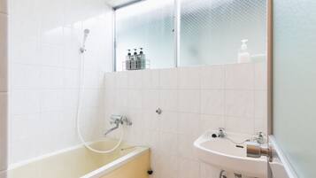 A bathroom with a bathtub, a sink, and a glass shower enclosure.