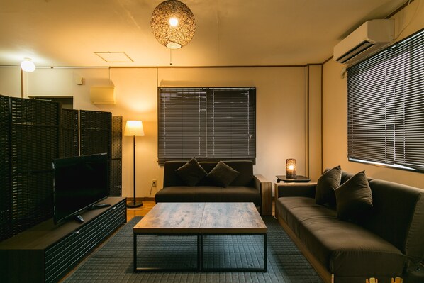 Una sala moderna con una televisión de pantalla plana, una mesa de centro, un sofá y una lámpara.