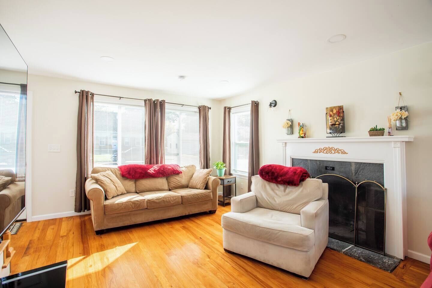 Una sala de estar con un sofá color crema, un sillón blanco y una chimenea.