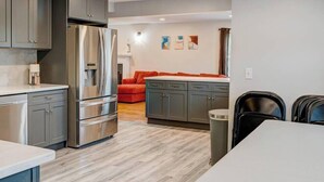 Una cocina moderna con electrodomésticos de acero inoxidable, armarios grises y un comedor con mesa y sillas.