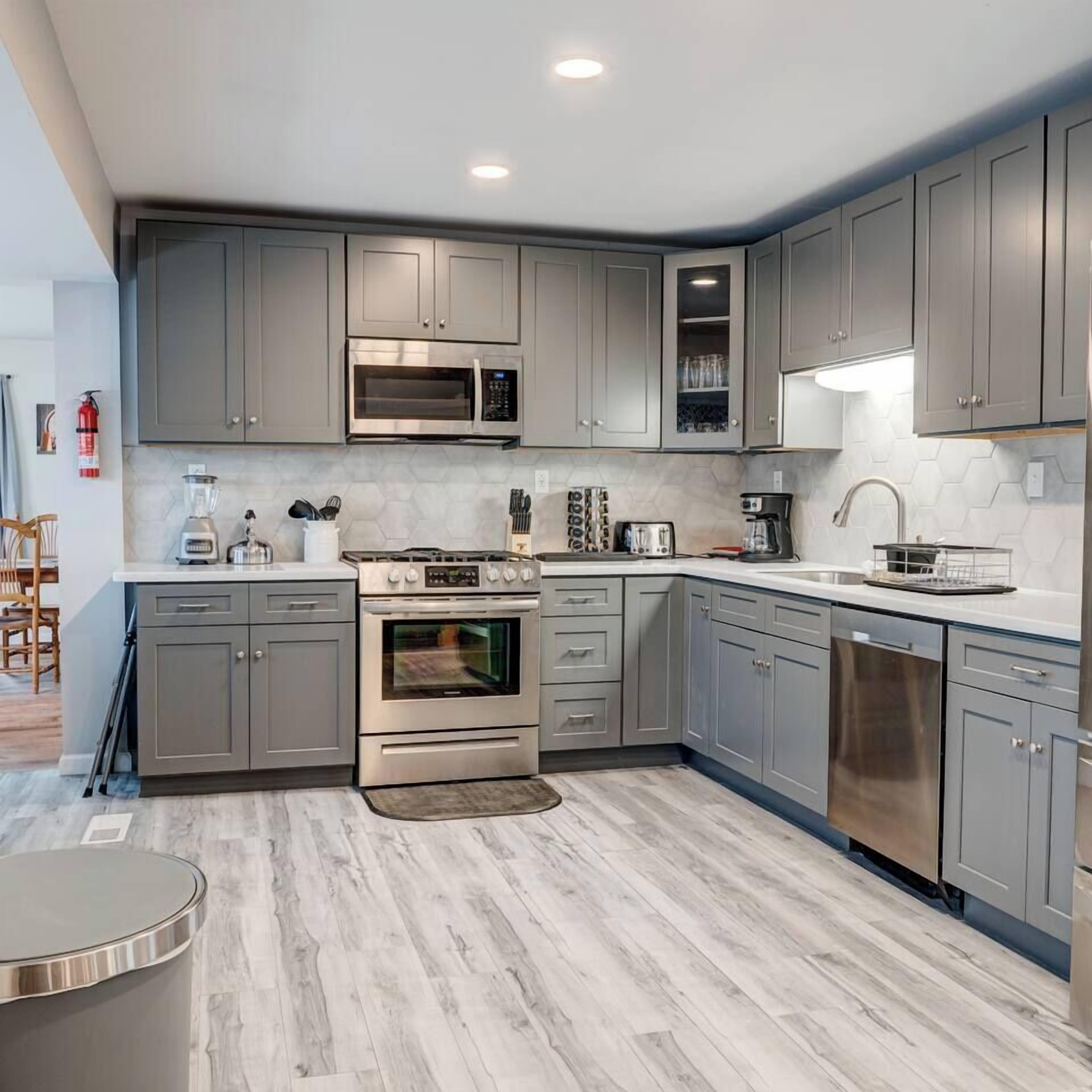 A modern kitchen with grey cabinets, a built-in microwave, a stove, and a dishwasher.