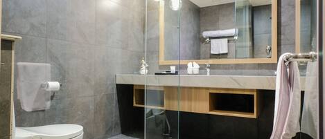 A modern bathroom with a glass shower enclosure, a toilet, a vanity with a mirror, and a towel rack.