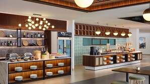 A modern hotel lobby with a bar area, buffet, and seating. - Artotel Batam (Batam)