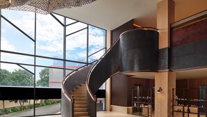 A modern interior with a spiral staircase, large windows, and a view of the outdoors. - Artotel Batam (Batam)