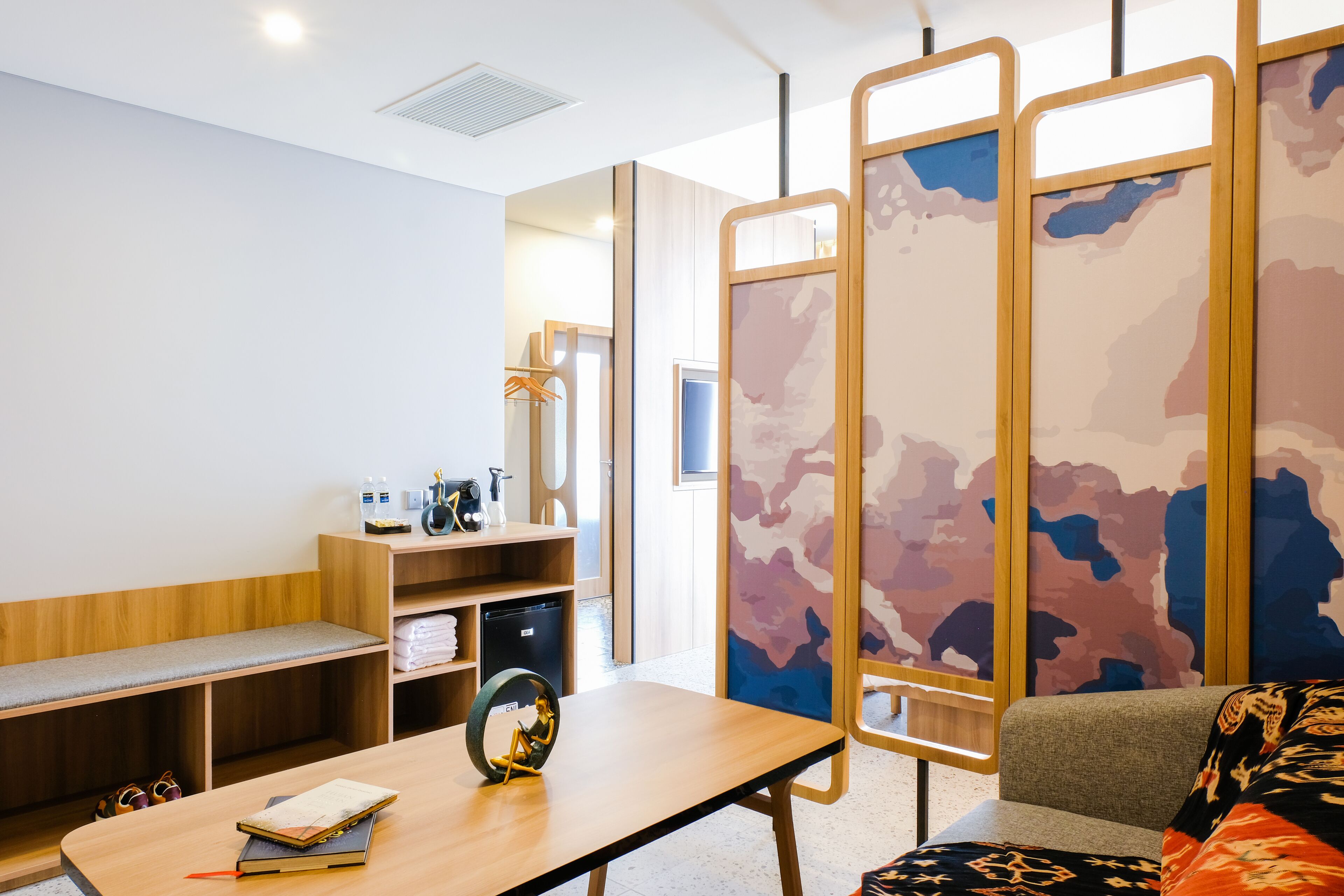 Una camera moderna con una panca in legno, un tavolo con un mappamondo, un divano e un ampio pannello decorato con un motivo camouflage.