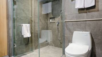 Un baño moderno con ducha envuelta en vidrio, inodoro y perchero para toallas.
