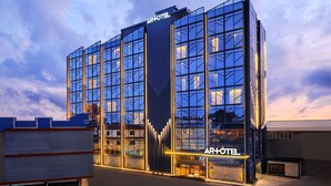A modern hotel with a glass facade, prominent signage, and a structured exterior design. - Artotel Batam (Batam)