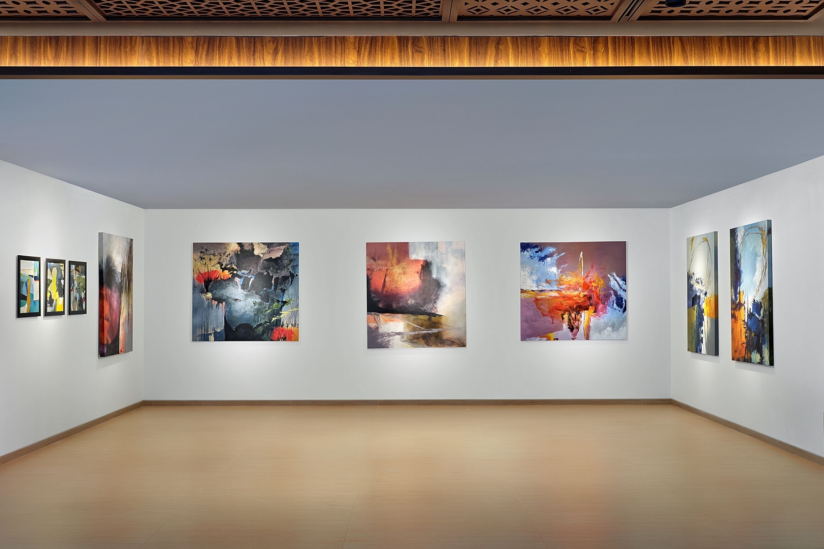 An art gallery with five large paintings on the wall and three smaller ones on the left.