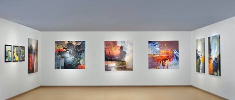 An art gallery with five large paintings on the wall and three smaller ones on the left.