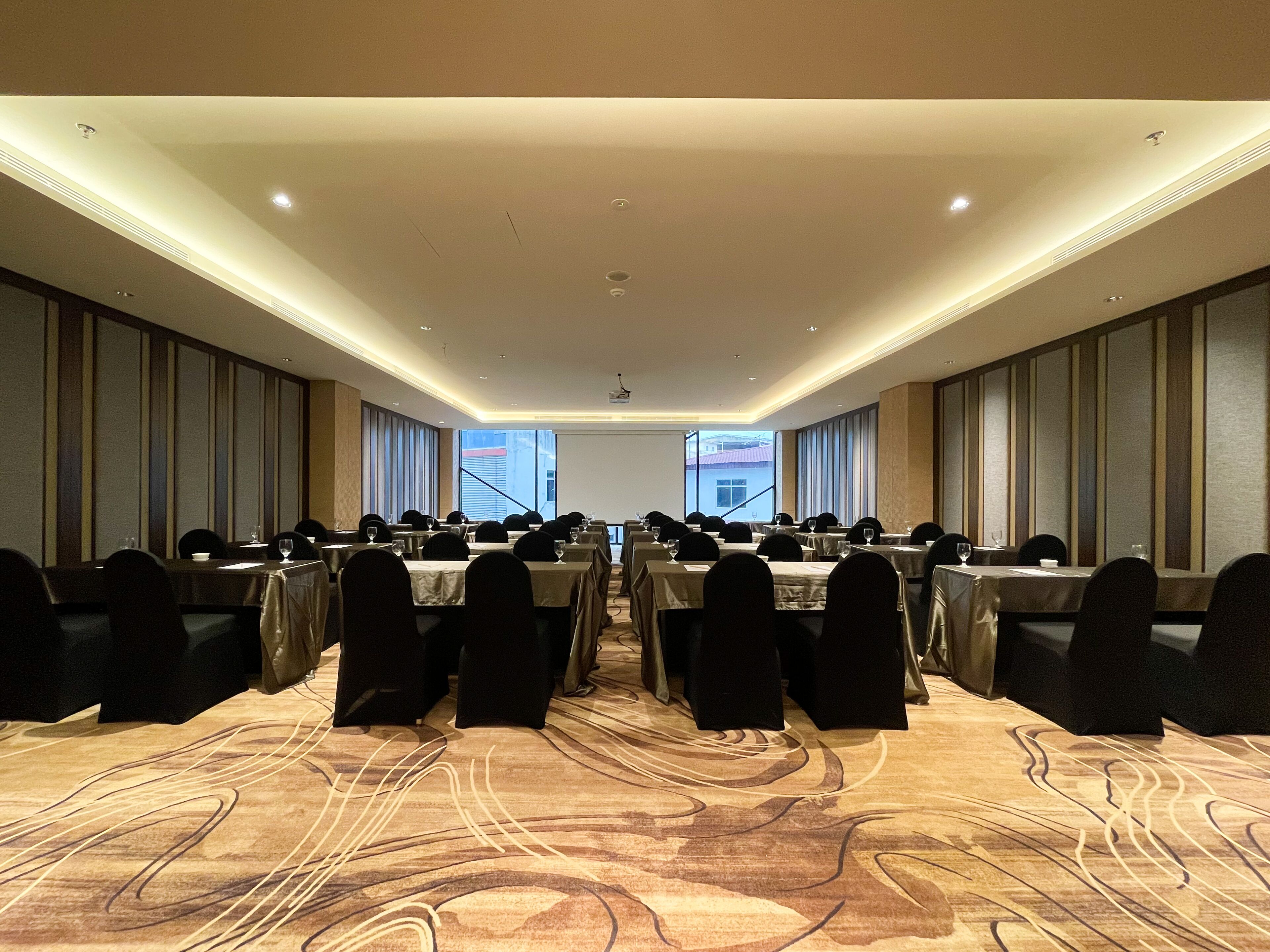 A conference room with long tables, chairs, and a carpeted floor.