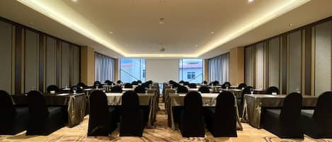 A conference room with long tables, chairs, and a carpeted floor.