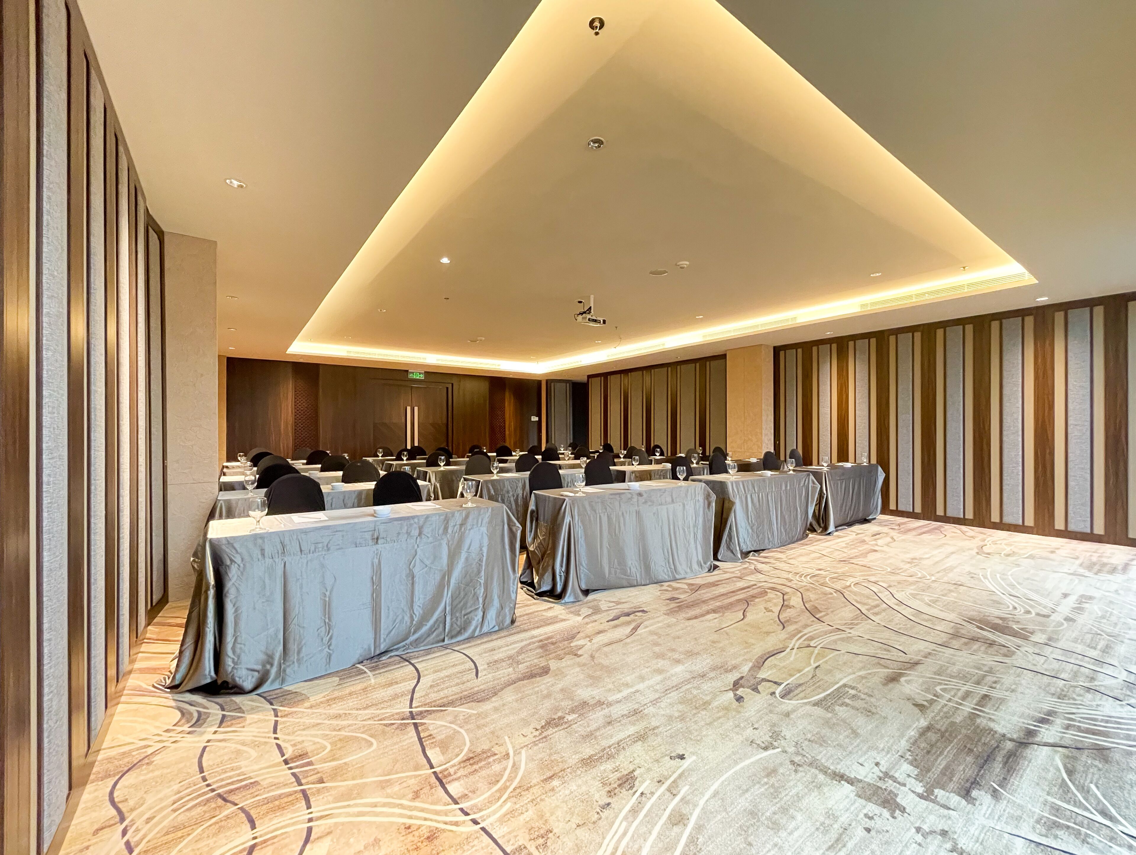 A conference room with tables set for a meeting, equipped with chairs and glassware.