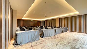 A conference room with tables set for a meeting, equipped with chairs and glassware.