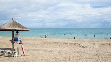 Na praia, espreguiçadeiras, guarda-sóis, toalhas de praia