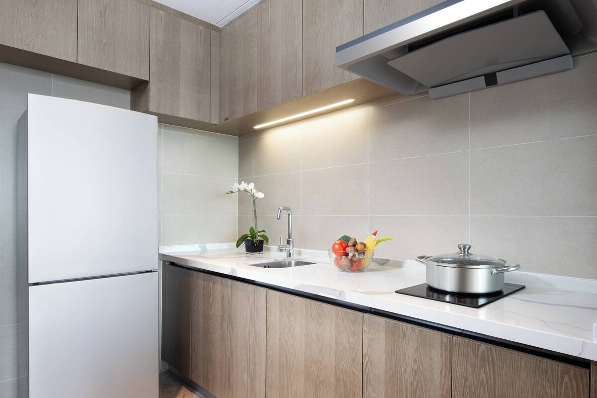 Een moderne keuken met houten kastjes, een wit aanrecht, een spoelbak en een ingebouwd fornuis.