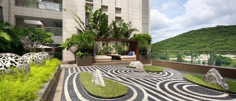 A rooftop garden with a patterned pathway, potted plants, and a seating area.