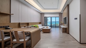 Ett modernt hotellrum med en matplats, en soffa, en TV och en balkong med utsikt över havet.