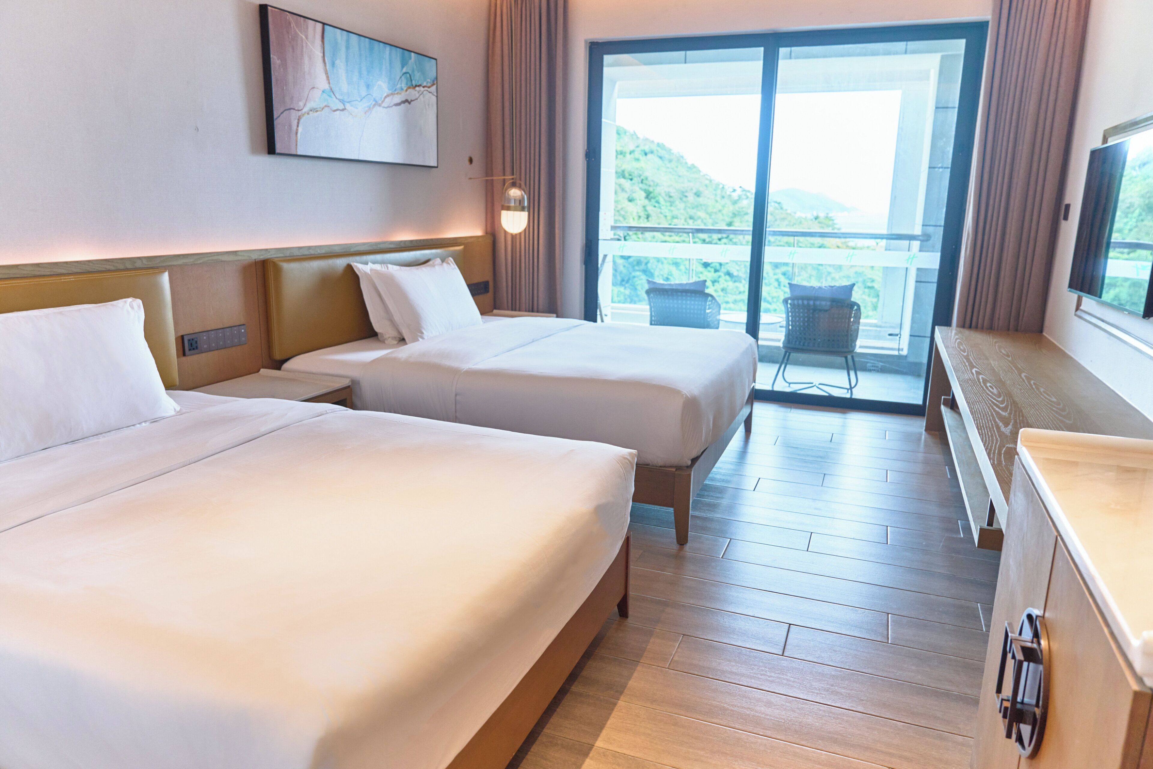 Habitación de hotel con dos camas, un ventanal grande y vistas a un paisaje montañoso.