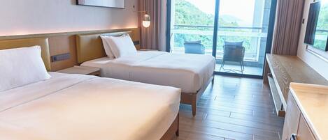 Habitación de hotel con dos camas, un ventanal grande y vistas a un paisaje montañoso.