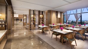 Un restaurant moderne au décor épuré et élégant, avec un mélange de mobilier en bois et en métal, et de grandes fenêtres offrant une vue sur le paysage urbain.