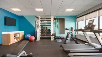 A gym with exercise equipment, a TV, and a window with a view.