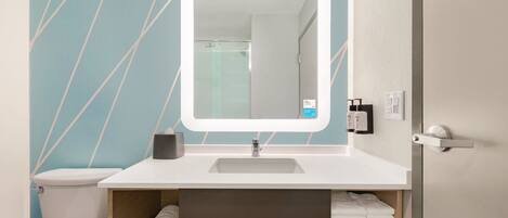 A bathroom with a white sink, a mirror, a toilet, and a towel rack.