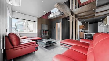A modern living room with red leather sofas, a flat-screen TV, and a glass coffee table.