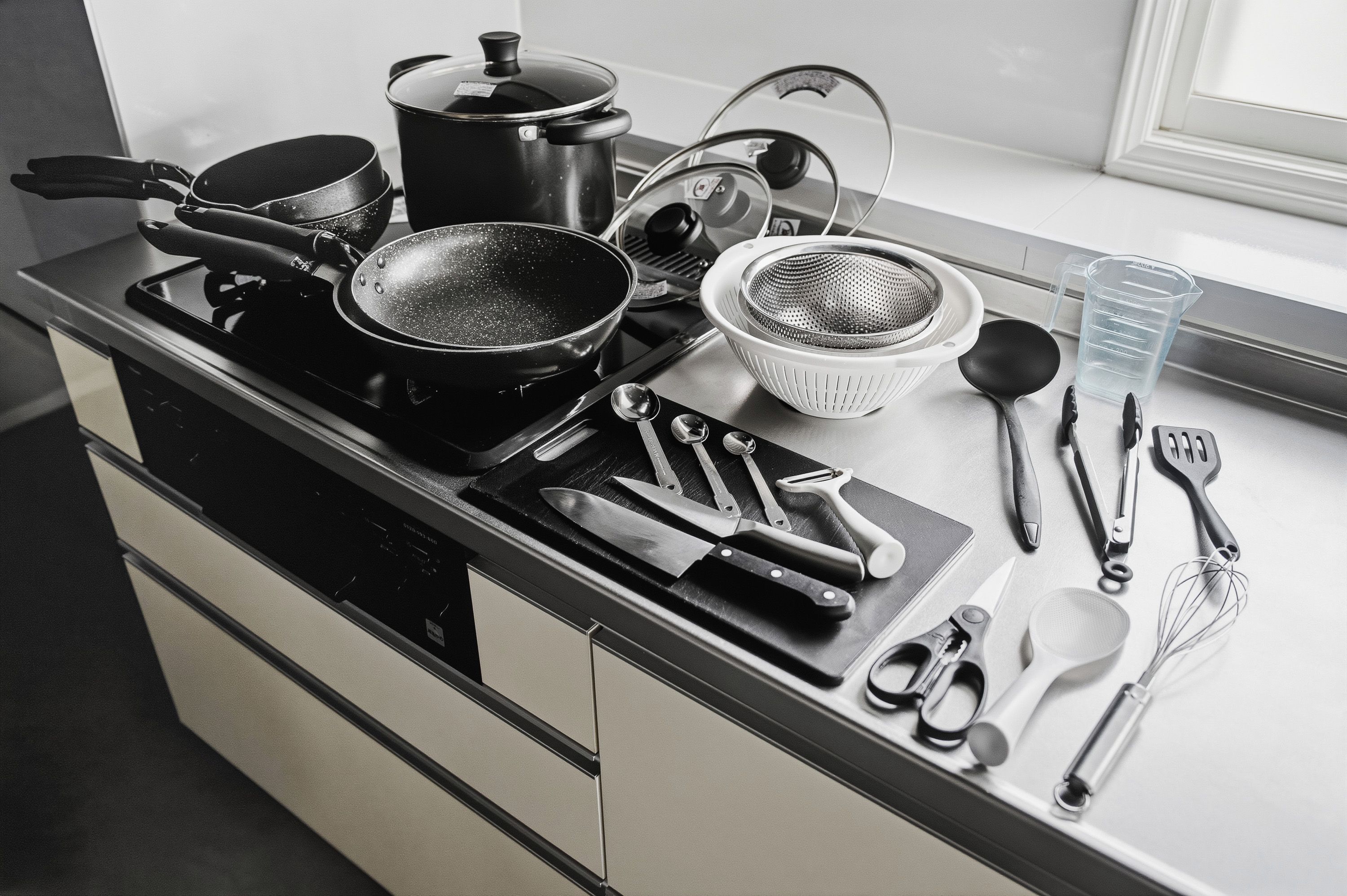 A kitchen counter with various cooking utensils, pots, and pans.