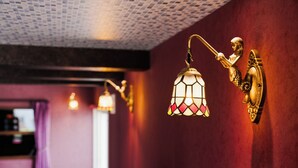 Wall-mounted lamps with a geometric pattern, a textured ceiling, and a red wall. - THE BEEHIVE AIOI (Otaru)