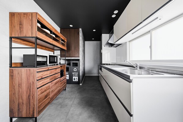 Una cocina moderna con armarios de madera, un lavamanos de acero inoxidable y un microondas integrado.