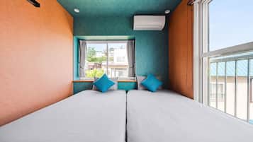 A room with two beds, a window, and an air conditioning unit.