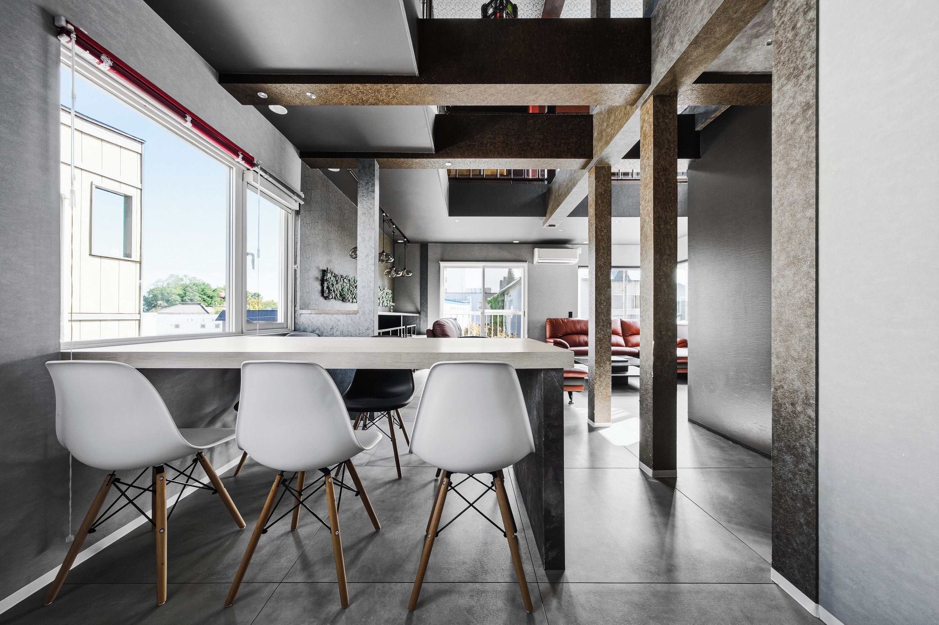 Una cocina moderna con una isla central, sillas blancas y vistas al exterior.
