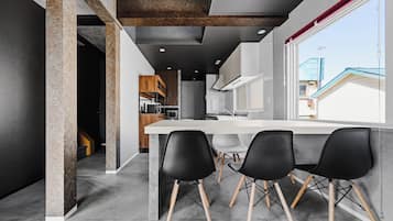 Una cocina moderna con comedor, que cuenta con un amplio ventanal, horno empotrado y una mesa con sillas.
